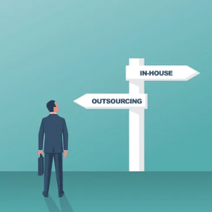 Businessman standing at a crossroads choosing between in-house development and outsourcing.